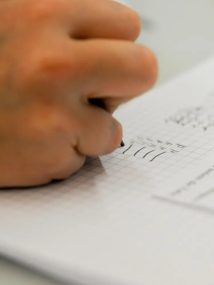 close up of hand writing on checkered paper